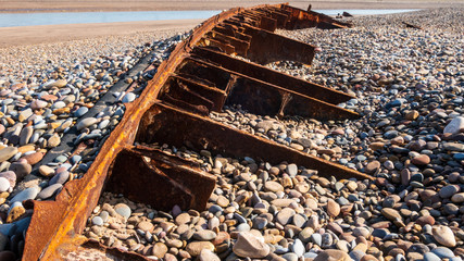 Rusty ship wrack sunken in stony beach
