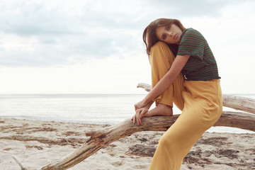beautiful fashionable girl on the beach dressed in a green sweatshirt and yellow pants, stylish...