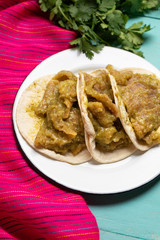 Mexican pork chicharron with green sauce tacos on turquoise background