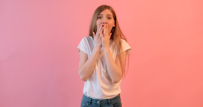 beautiful young girl is worried , a woman with a terrified face, on a pink background