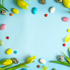 Naklejka na ściany i meble Happy Easter frame with yellow tulips, easter eggs, quail eggs, pussy-willow twigs, colored sweet balls with place for text in the middle. Easter background top view,copy space