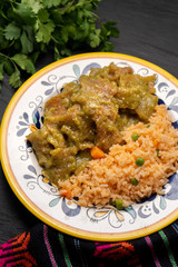 Mexican pork chicharron with green sauce and rice on dark background