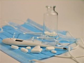 COVID-19 epidemic,blue disposable medical masks,thermometer,pills and medical ampoules glass on a white background.Coronavirus drugs.