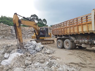 Backhoe digging for gypsum ore And loaded at the ten-wheeled truck at the mine