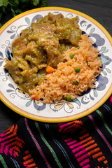 Mexican pork chicharron with green sauce and rice on dark background
