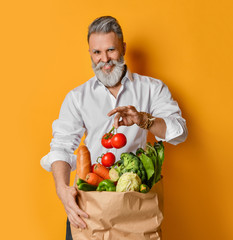 Cool old mature senior man with gray beard shopping hold grocery shopping bag with healthy organic vegetables