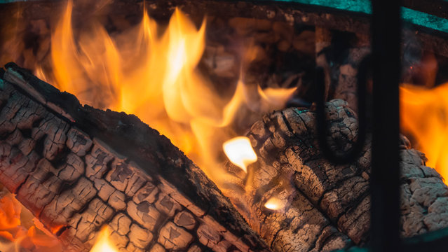 Burning Fire.Closeup. Bonfire, burning trees logs. Warm, cozy burning fire in a brick fireplace. Red, orange fire flame and smoke.Template.Place for text.