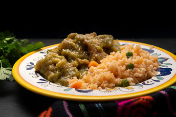 Mexican pork chicharron with green sauce and rice on dark background