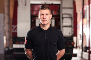 Professional fireman portrait. Firefighter wearing shirt uniform and fire truck in the background.