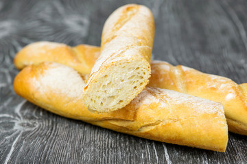 Bread baguettes made of wheat flour in a cut on a gray wooden background