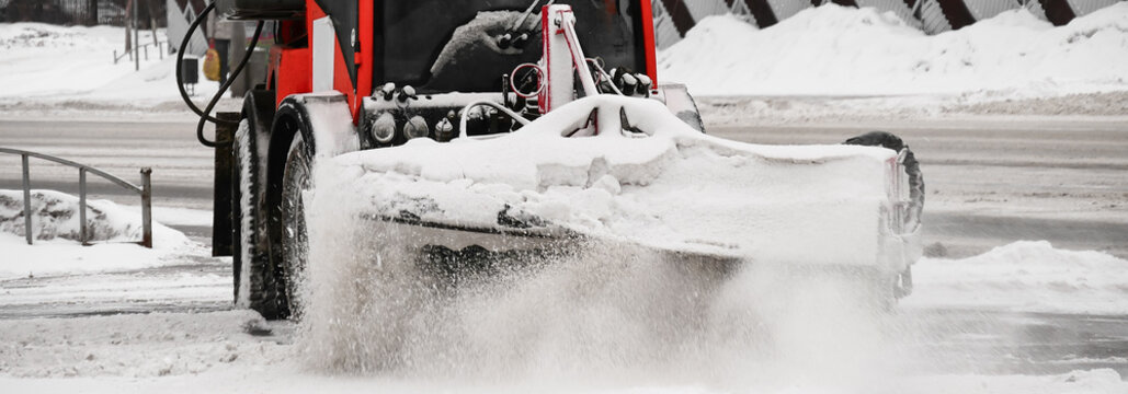 Snow machine cleans snow. Snow plow removing dirty and gray snow . Close-up. Spring or Autumn cleaning of the city and maintenance of streets by municipal services.