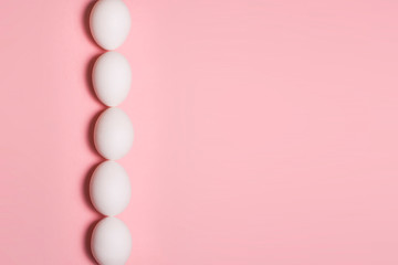 Close up of white eggs in line on plain pink background with copy space / Abstract of food for easter / Background texture / Horizontal. Organic food concept. Food market and delivery service.