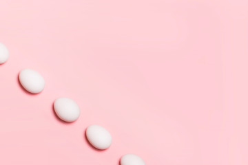 Close up of white eggs on plain pastel pink background with copy space / Abstract of food for easter / Background texture on diagonal. Food market.Horizontal. Food blog template. Organic food concept.