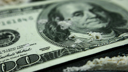 drugs and money. drug addiction. Twisted banknote through which sniffing cocaine. A hundred dollars bills and a lot  cocaine scattered on the table. Addict use Illegal Drugs.