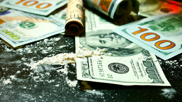 money and cocaine. Addiction. Drug use.  Hundred-dollar bills, white powder (like cocaine) on the black table close-up. Illegal drugs and dirty money. A lot cocaine.