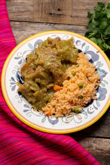 Mexican pork chicharron with green sauce and rice on wooden background