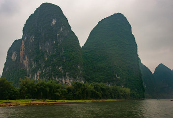 Guilin, China - May 10, 2010: Along Li River. Landscape of rounded twin forested karst mountain...