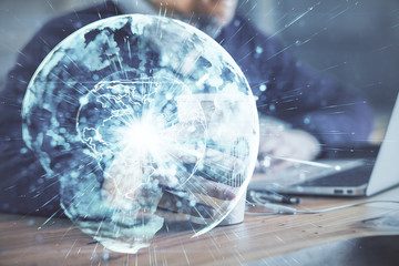 Obraz premium Double exposure of businessman working on laptop on background. International business hologram in front. Concept of success.