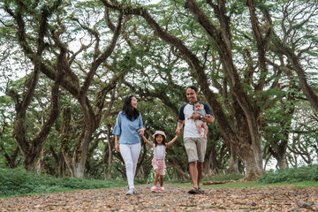 Obraz premium Asian families enjoy holidays together, father, mother and two children walking in the park