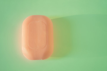 Orange bar of soap on a green table. Top view.