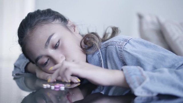 Depressed teenage girl with pills on the table