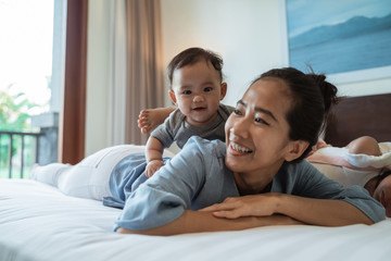 Fototapeta premium mother lying in bed with her daughter while playing in the bedroom