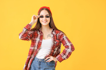 Young woman with stylish sunglasses on color background