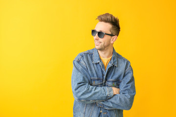 Young man with stylish sunglasses on color background