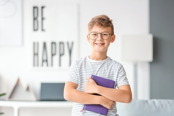 Little boy with book wearing glasses at home