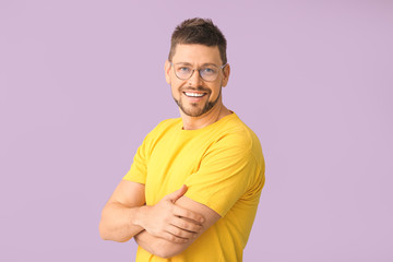 Handsome man with glasses on color background