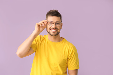 Handsome man with glasses on color background