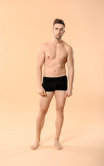 Handsome man in underwear on color background