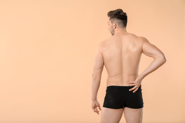 Handsome man in underwear on color background