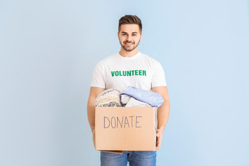 Volunteer with donations for poor people on color background