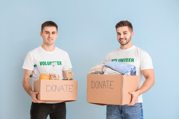 Volunteers with donations for poor people on color background