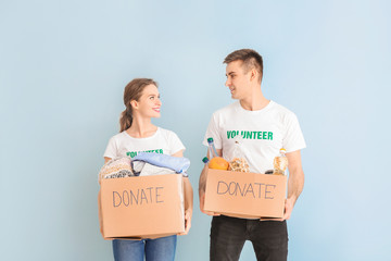 Volunteers with donations for poor people on color background