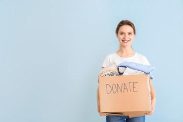 Volunteer with donations for poor people on color background