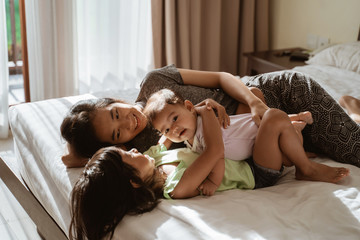 two little daughter lying in bed with their mother next to them in the bedroom