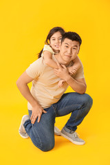 Happy Asian man with his little daughter on color background