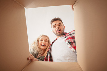 Emotional young couple with open moving box, view from inside