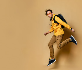 Fototapeta na wymiar Portrait of a young student man jumping in the studio on a beige background