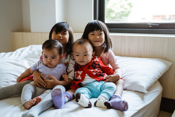Fototapeta premium four Asian children smile when sitting on the bed hugging each other
