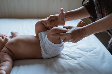 mother stretch her baby feet on the bed giving massage