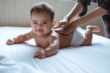 prone baby happy is smile his back by his mother while lying in the bedroom