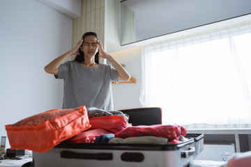 asian mother has a headache when preparing clothes and bags for travel
