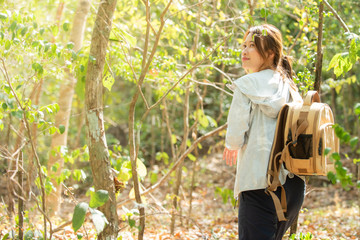 Happy young Asian beautiful woman with backpack hiking on mountain forest dirt road with smiling face. Confidence woman enjoy and having fun with outdoor adventure leisure activity in summer vacation