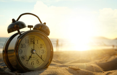 Morning of a new day, alarm clock on the beach sunlight in morning. Health and holiday concept.