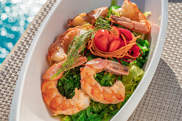 Shrimps and green salad starters on a white plate