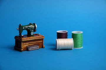 needlework kit and sewing machine on blue background. Image contains copy space.
