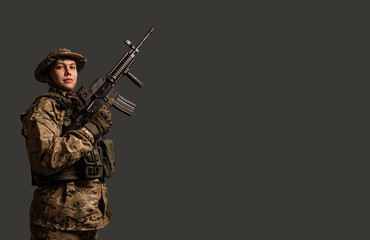 A bottom-up portrait view of a soldier in a military camouflage uniform wearing a  helmet, body...
